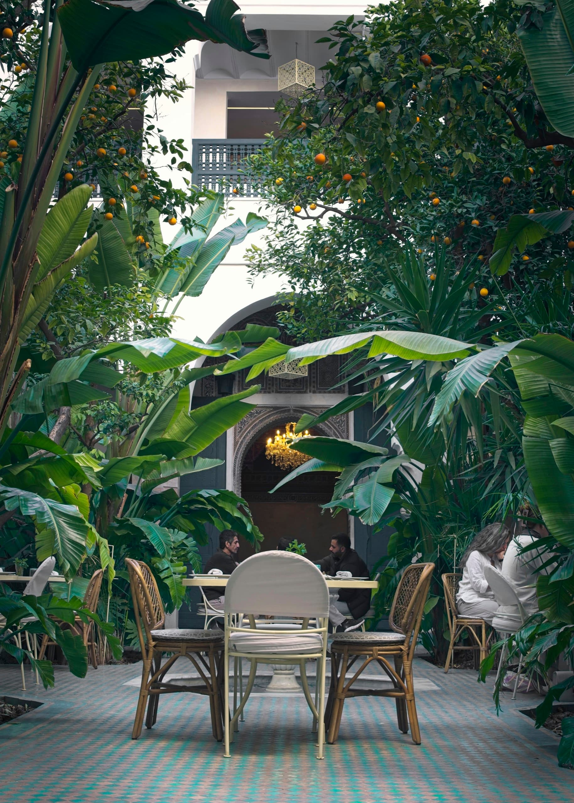 Table dressée et fauteuils de rotin dans un restaurant de jardin, sous les bananiers